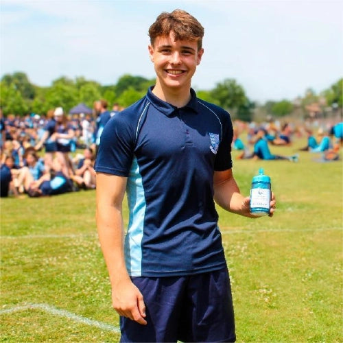 Harrison Nott in school sports kit, standing on a sunny playing field, holding a CoolTowel blue bottle