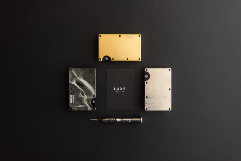 The Ridge Wallet in three finishes — gold, carbon fiber, and brushed titanium